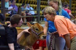 Dairy Judge speaking with participant and helper, Jersey Calf also present