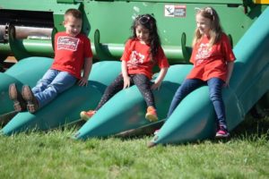 3 Children Playing around parked farm machinery