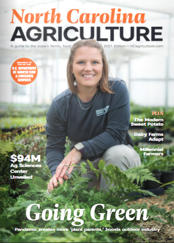 Woman sitting among plants in a green house, cover of NC Agriculture Magazine